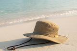 Wide-brim UPF sun hat on bright beach sand