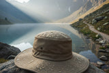 Wide-brim water-resistant sun hat on rock near mountain lake with water droplets