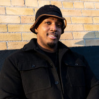 Model wearing the black side of the Flip Reversible Bucket Hat with a modern streetwear outfit, demonstrating the versatile reversible design for casual everyday wear.