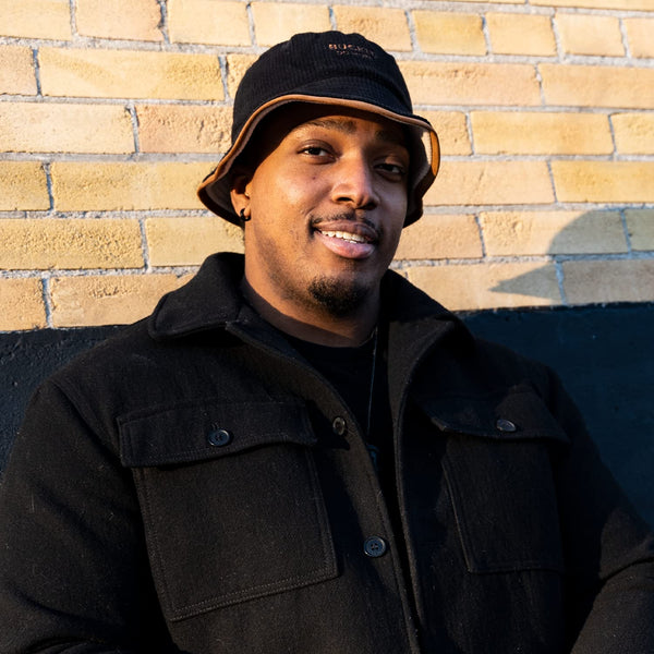 Model wearing the black side of the Flip Reversible Bucket Hat with a modern streetwear outfit, demonstrating the versatile reversible design for casual everyday wear.